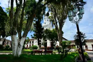 Foto van een groen parkje met een mooi wit kerkje in Colombia.