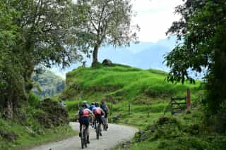 Veloglobe deelnemers aan het fietsen op een gravelparcour in smalle wegen in Colombia.