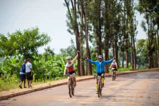 Geertrui van Look, oprichtster van Veloglobe, zwaait vrolijk met Veloglobe's Rwandese gids tijdens een fietsreis in Rwanda.