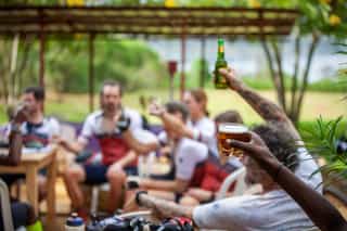 Veloglobe deelnemers rusten uit na een lange dag fietsen en heffen hun drankjes op in de lucht als een toast.
