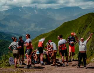 Des cyclistes Veloglobe font une pause sur un col en Géorgie, face aux vallées verdoyantes et aux sommets du Caucase.